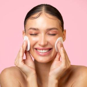 Home daily skincare excited young lady cleaning face with cotton pads smiling doing skin care routine.jpg